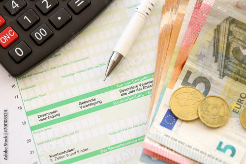 Filling greman tax form process with pen and euro money bills close up. Tax paying period and deadline photo