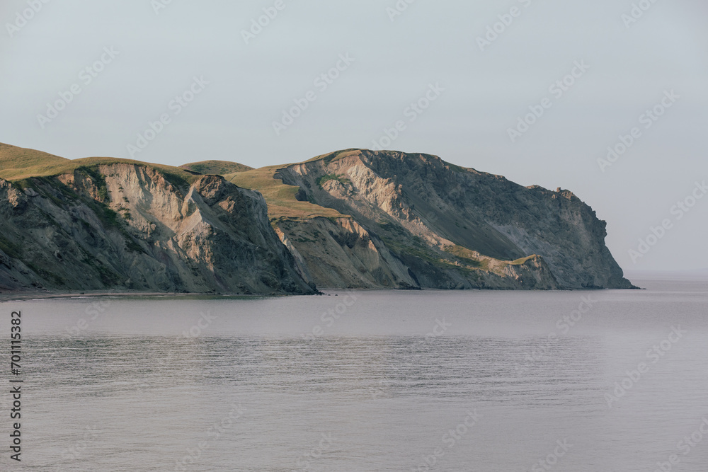 vue sur un rocher gris en bord de mer avec du gazon sur le dessus en été