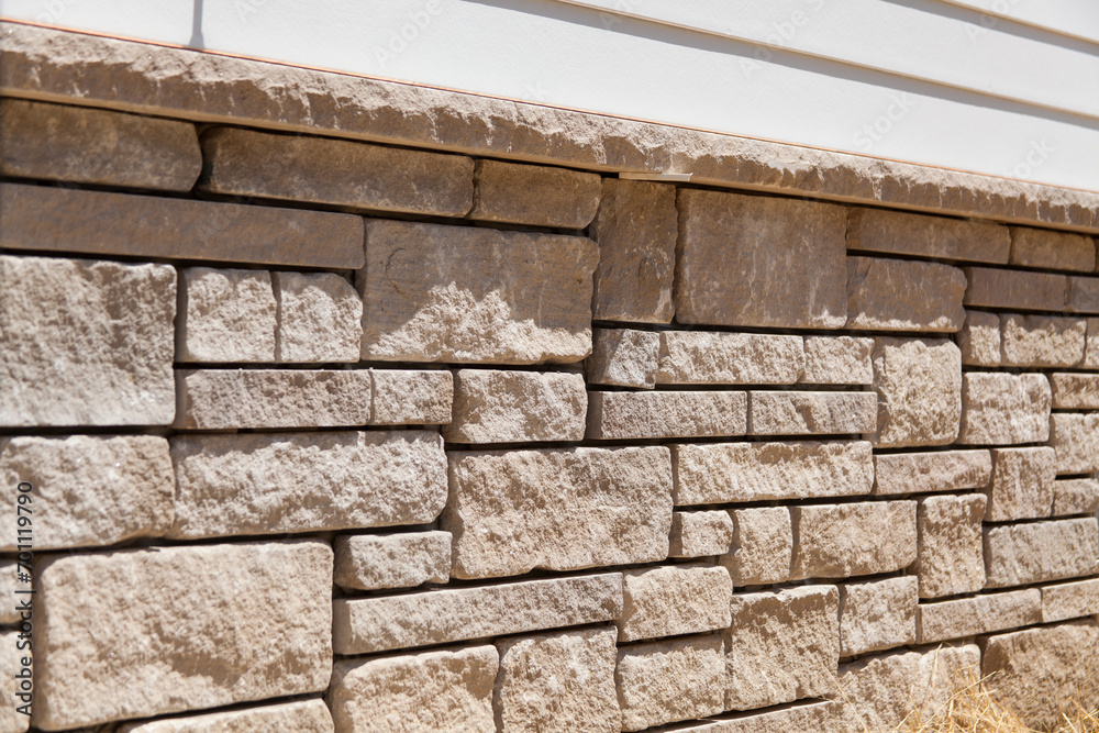 Natural stone veneer instal on the foundation of a home. Stone mason work. - obrazy, fototapety, plakaty 