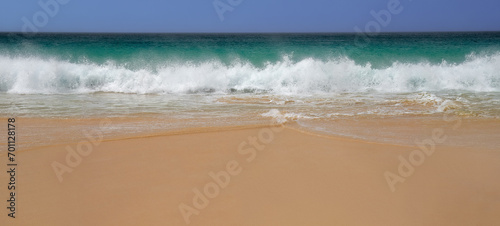 A wave with turquoise water and white foam approaches on a windy day at Boa Vista's beach, Cape Verde.