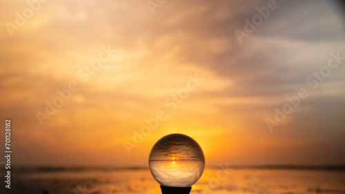 Colorful yellow, orange sunrise at the beach, reflected in crystal lens ball on a stand glass photography ball reflecting the colors of the sunrise at North Padre Island National Seashore in Texas 