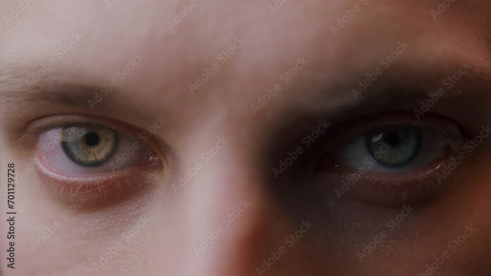 Extreme close-up colored eyes of young blonde man looking at camera