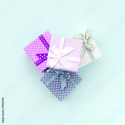 Pile of a small colored gift boxes with ribbons lies on a violet background. Minimalism flat lay top view.