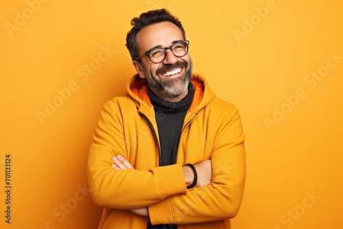 Portrait of happy mature man in yellow hoodie and glasses on yellow background photo
