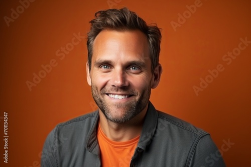 Portrait of a handsome young man smiling at camera over orange background
