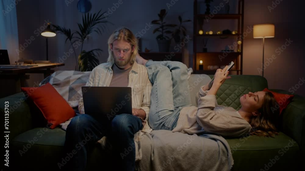 Woman changing positions around man with laptop on couch Woman changing positions around man with laptop on couch