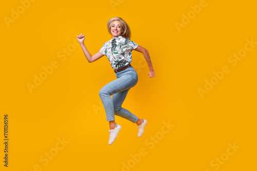 Fototapeta Naklejka Na Ścianę i Meble -  Full length photo of positive nice woman wear print stylish blouse denim pants hurry run shopping isolated on yellow color background