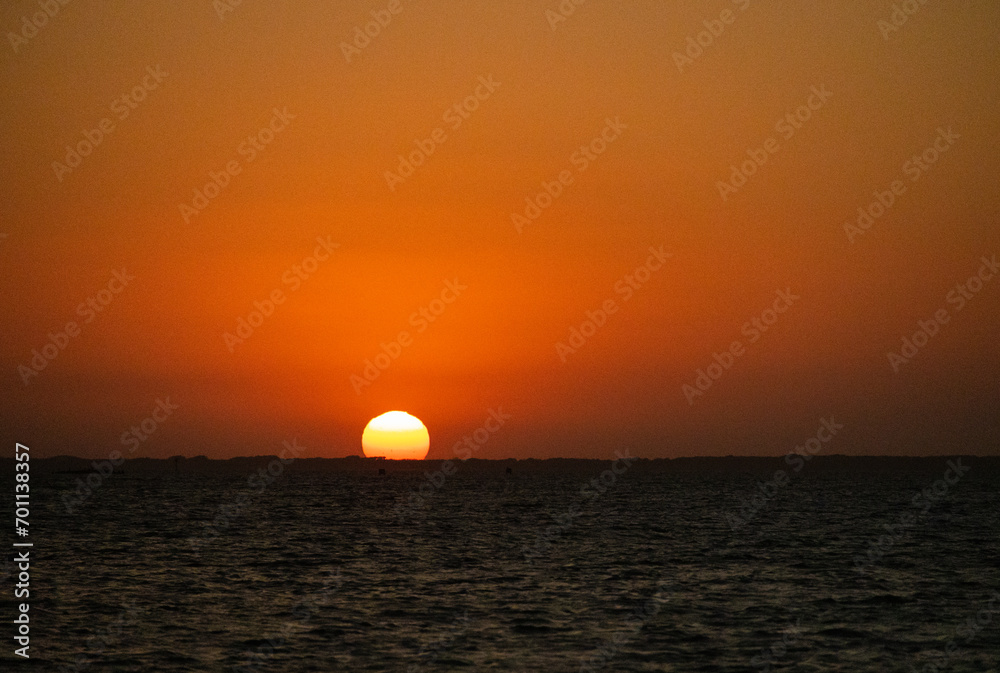 Glorious low-angle egg yolk Sunset over the calm waters of Laguna Madre between North Padre Island and Flour Bluff in Southern Texas