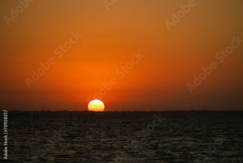 Fototapeta Naklejka Na Ścianę i Meble -  Glorious low-angle egg yolk Sunset over the calm waters of Laguna Madre between North Padre Island and Flour Bluff in Southern Texas