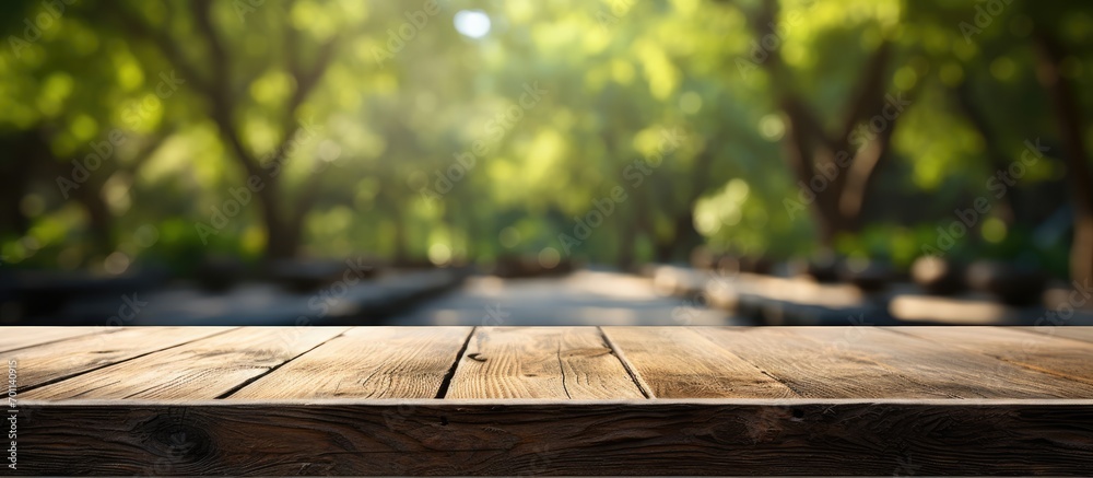 Fototapeta premium Empty table from old wood in front of blurred background. Perspective of blurry trees in forest
