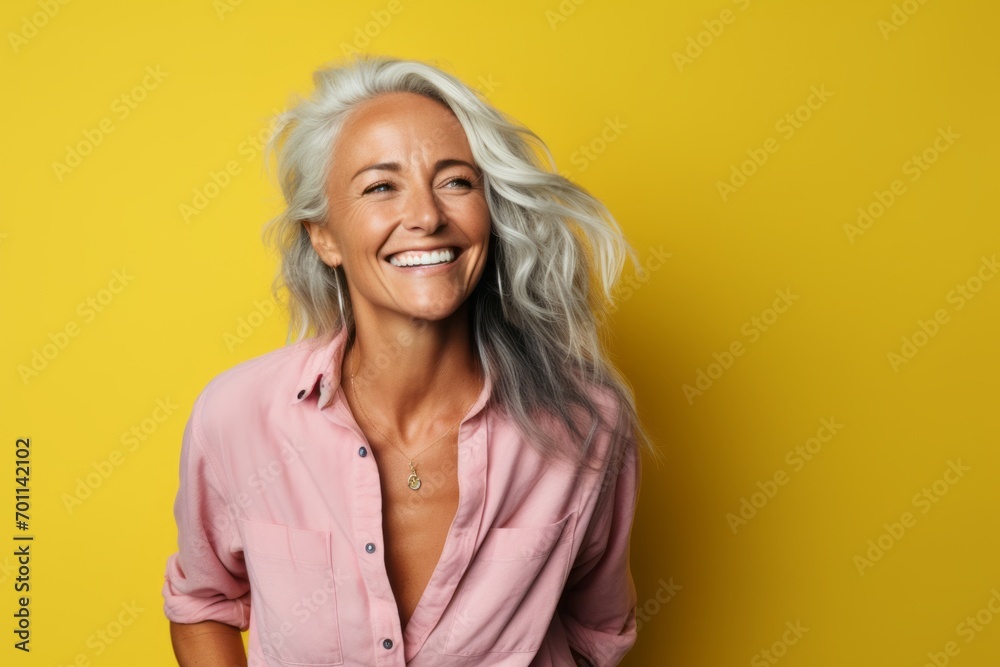 Beautiful senior woman laughing and looking at camera over yellow background.