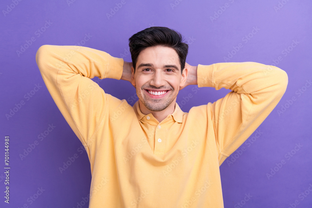 Photo portrait of attractive young man hands behind head have rest wear trendy yellow clothes isolated on violet color background Photo portrait of attractive young man hands behind head have rest wear trendy yellow clothes isolated on violet color background