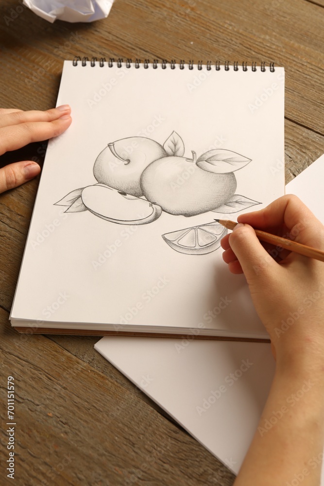 Woman with graphite pencil drawing fruits in sketchbook at wooden table, closeup Woman with graphite pencil drawing fruits in sketchbook at wooden table, closeup