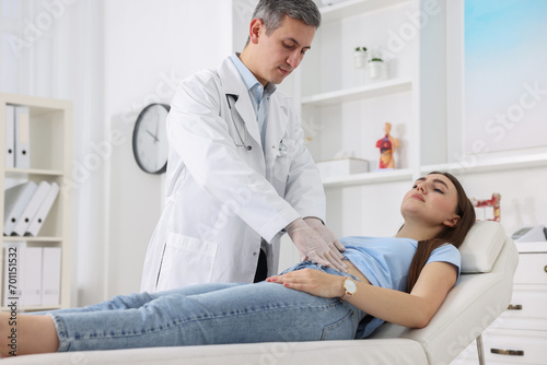 Schilderij op canvas Gastroenterologist examining patient with stomach pain on couch in clinic