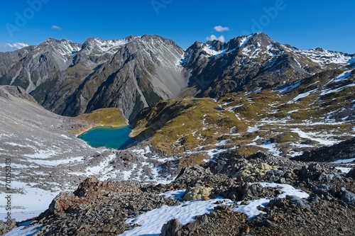 Breathtaking Blue Lake Amidst Snowy Rocky Mountains along Robert Ridge Route, New Zealand