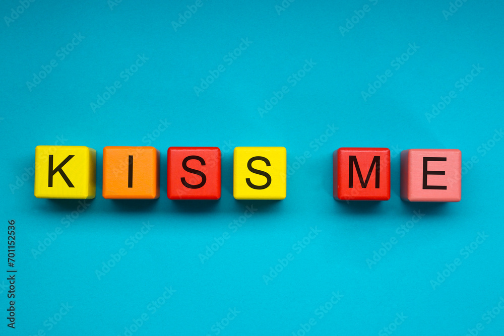 Colorful cubes with phrase Kiss Me on light blue background, flat lay Colorful cubes with phrase Kiss Me on light blue background, flat lay
