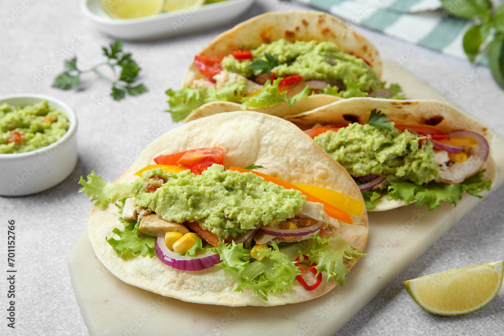 Delicious tacos with guacamole, meat and vegetables on light grey table, closeup Delicious tacos with guacamole, meat and vegetables on light grey table, closeup