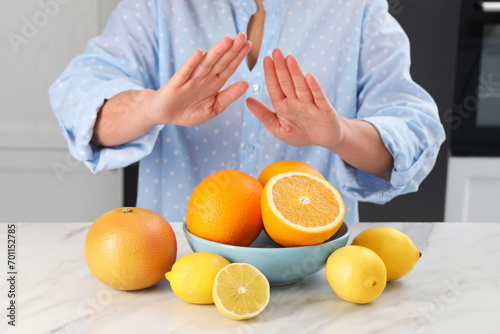 Woman suffering from food allergies refusing eat citrus fruits at light marble table indoors, closeup