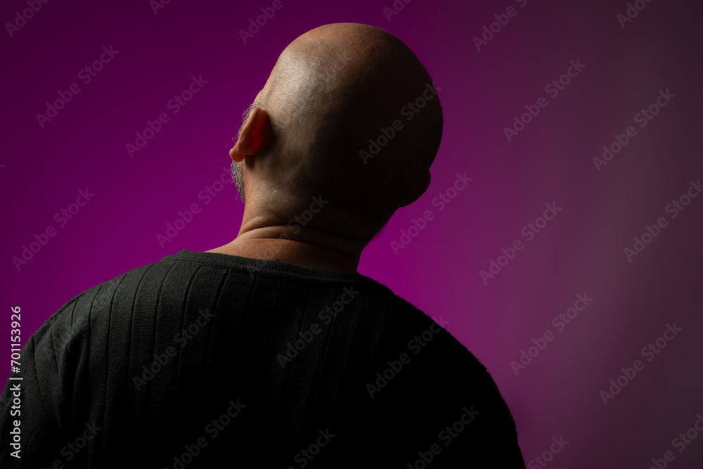 Handsome, bald and bearded man with his back to the camera looking up. Handsome, bald and bearded man with his back to the camera looking up.