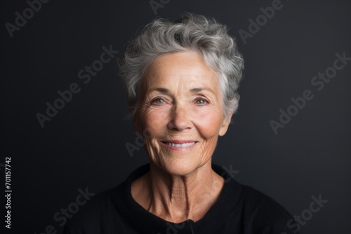 Portrait of a smiling senior woman on black background. Looking at camera.