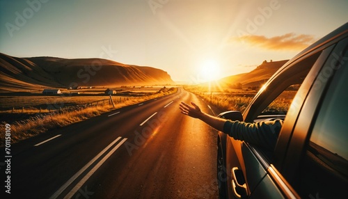Road trip concept - hand held out of an open window, sunset in the foreground photo