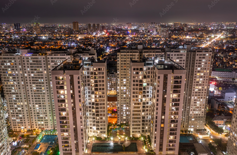 Aerial view of big city residential building and illuminated urban sprawl at night.