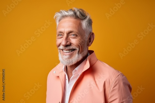 Portrait of happy senior man looking at camera and smiling while standing against orange background