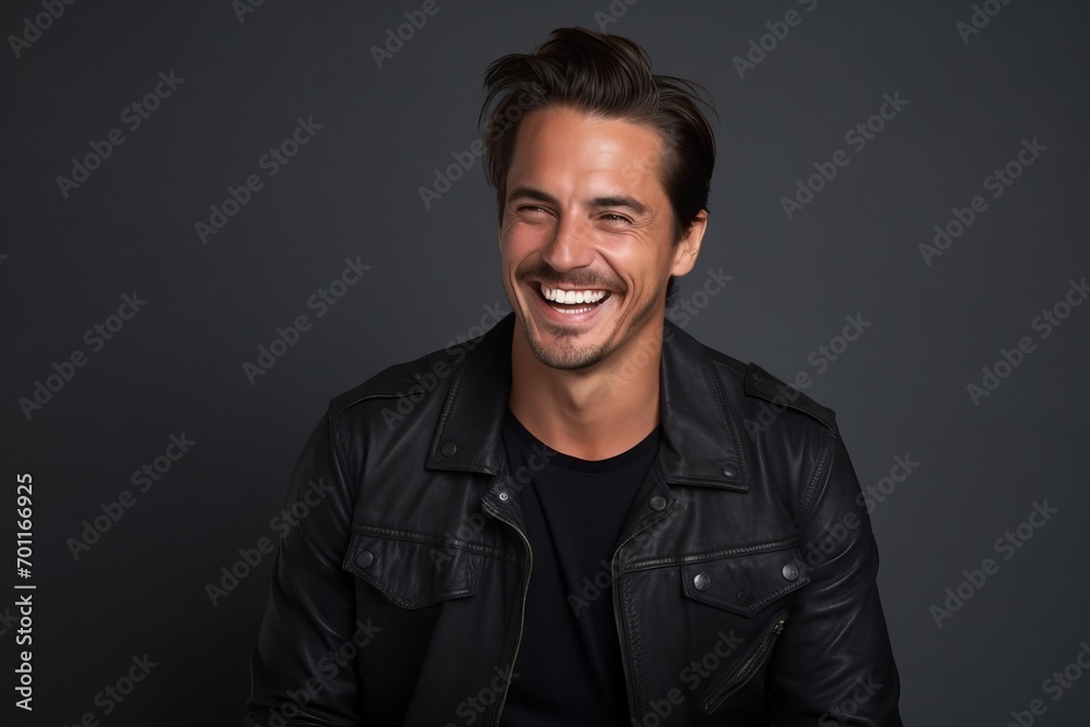 Portrait of a smiling handsome man in leather jacket on grey background Portrait of a smiling handsome man in leather jacket on grey background