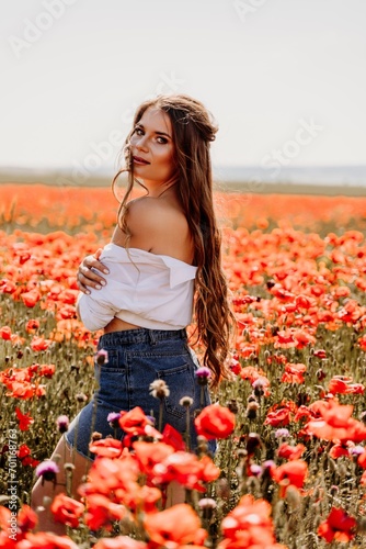 Woman poppies field. Side view of a happy woman with long hair in a poppy field and enjoying the beauty of nature in a warm summer day.