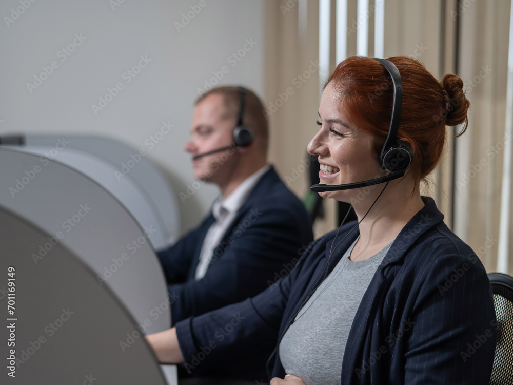 Two friendly call center employees answer customers by phone. Man and woman woman talking on a headset in the office. Two friendly call center employees answer customers by phone. Man and woman woman talking on a headset in the office.