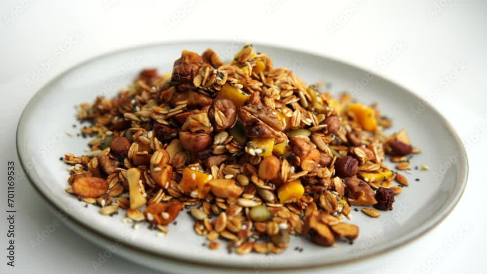 Healthy organic granola breakfast flakes with almonds, cashew nuts walnuts, hazelnuts, pumpkin seeds and cranberries circle rotation close up top view. Healthy organic granola breakfast flakes with almonds, cashew nuts walnuts, hazelnuts, pumpkin seeds and cranberries circle rotation close up top view.