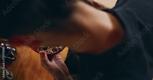 Closeup of bowl of noodles, hands and person is eating food, nutrition and sushi with chopsticks in Japan. Hungry for Japanese cuisine, soup and Asian culture, traditional meal for lunch or dinner photo