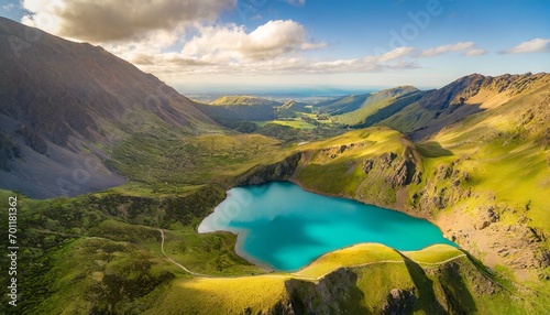 Aerial view of a turquoise glacial lake nestled in a vibrant green valley during golden hour.