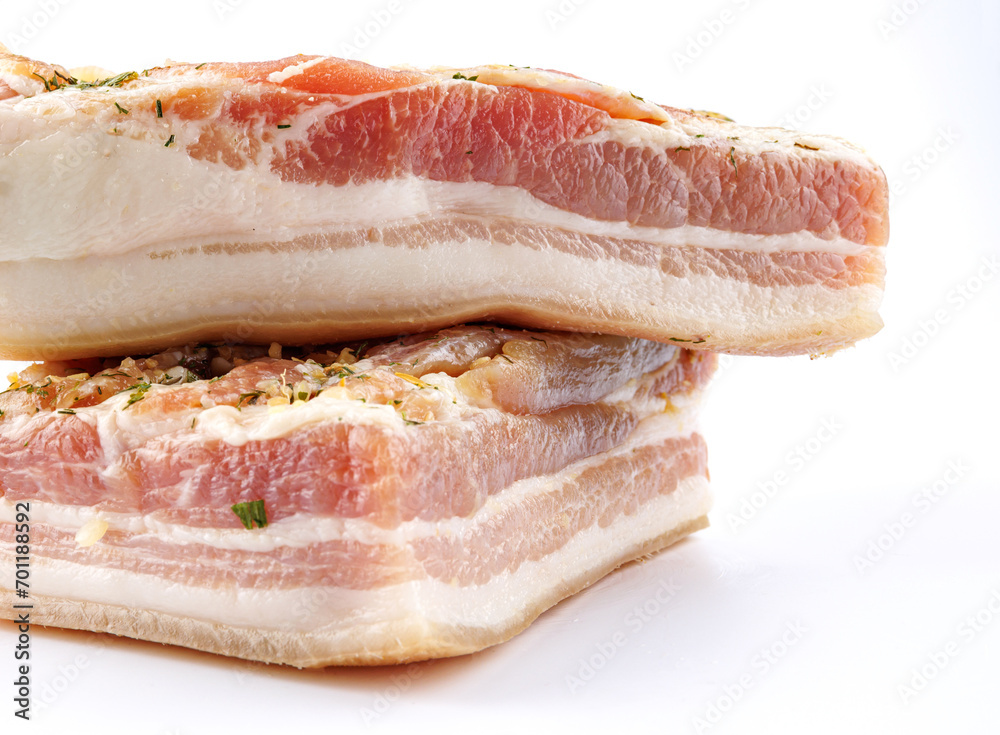 Appetizing salty lard with layers of meat with garlic and herbs. Two pieces of salted lard on a white background. Appetizing salty lard with layers of meat with garlic and herbs. Two pieces of salted lard on a white background.