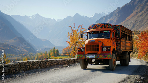 Vibrant orange truck on Skardu's roads, adorned with geometric patterns.