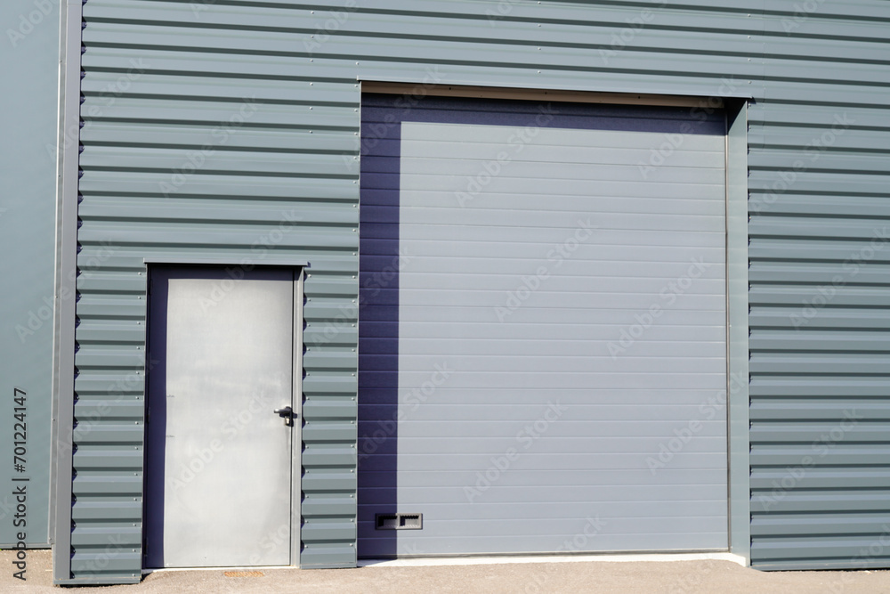 Fototapeta premium entrance roll-down facade shutters on gray building fire exit door in commercial industrial unit