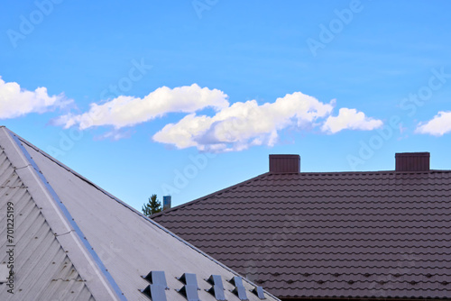Brown gray silver metal tile profile on the roof of a house and blue clear sky