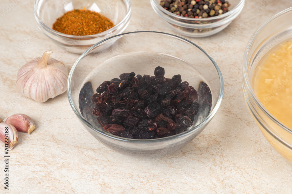 Soaking raisin before cooking in modern multi cooker pilaf in bowls on a kitchen table near other prepared ingredients. Cooking pilau with meat in multicooker. Soaking raisin before cooking in modern multi cooker pilaf in bowls on a kitchen table near other prepared ingredients. Cooking pilau with meat in multicooker.