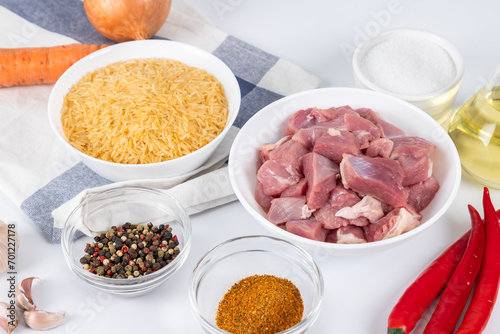 Prepared raw ingredients for cooking pilaf in modern multi cooker in kitchen on a table. Cooking pilau with meat in multicooker.