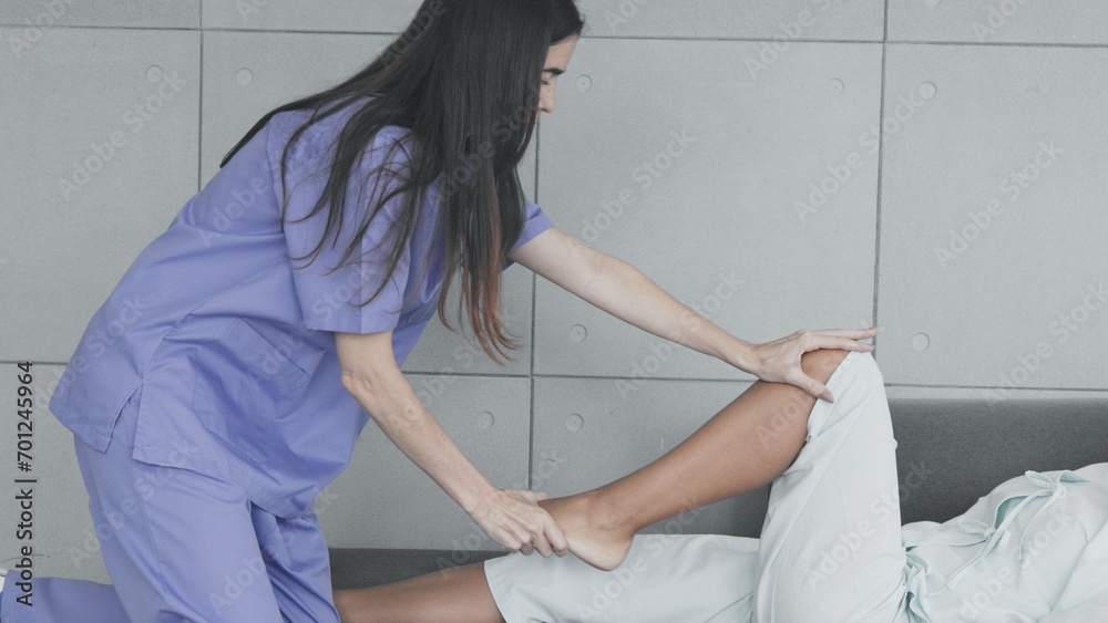 Doctor doing physical therapy on young female patient knee in clinic, Treatment of injured knee joint in young female patient Doctor doing physical therapy on young female patient knee in clinic, Treatment of injured knee joint in young female patient