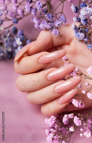 Female hands with pink nail design hold gypsophila flowers.
