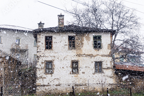 Old village house and falling snow