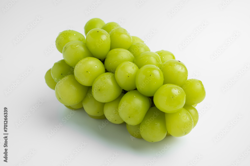 A single Shine Muscat grape with water droplets on a white background