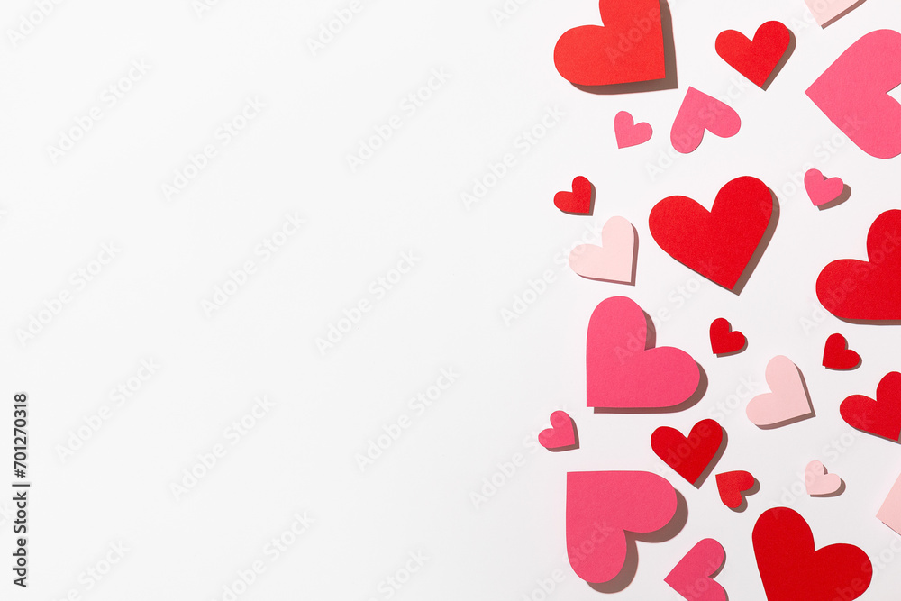 Small red and pink paper hearts on a light background. Valentine's Day. Top view. Space for text.