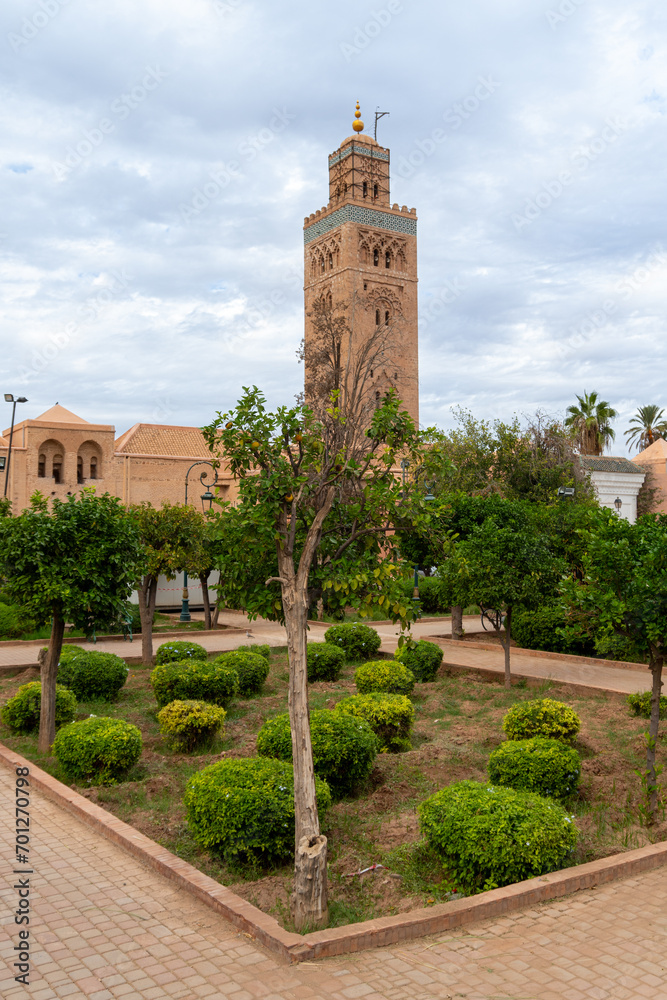 Photo of the tower of the Koutoubia mosque seen from the gardens next to the mosque. Cloudy day.