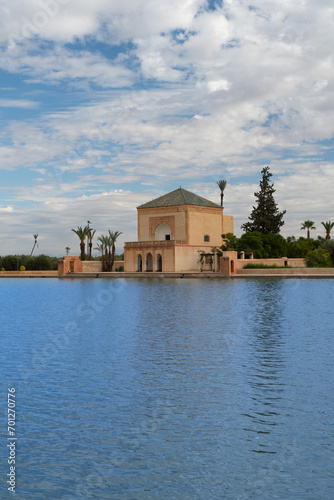 Photo of the Menara Gardens in the city of Marrakech. Photo of the lake with the house at the end of the lake. The house reflected in the lake. Cloudy day.
