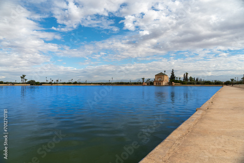 Photo of the Menara Gardens in the city of Marrakech. Photo of the lake with the house at the end of the lake. The house reflected in the lake. Cloudy day.