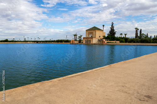 Photo of the Menara Gardens in the city of Marrakech. Photo of the lake with the house at the end of the lake. The house reflected in the lake. Cloudy day.