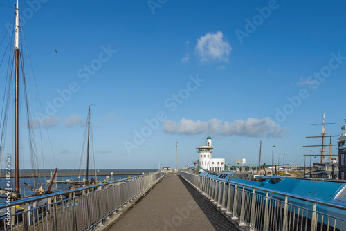 View on the Hoge Willemskade, walkway of the Nieuwe Willemshaven, in Waddensea harborcity Harlingen, Friesland, the Netherlands, with view to the harbor control tower , train and sailingboats photo