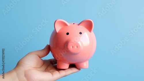 Holding a piggy bank against a soft blue backdrop with one hand. Generative AI